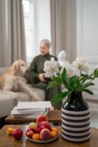 pet trust, image of senior woman with dog inside with flowers in foreground
